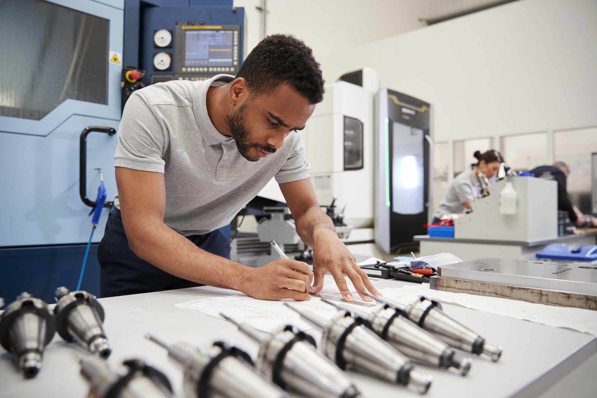 Male Engineer Measuring CAD Drawings In Factory